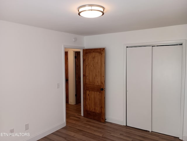 unfurnished bedroom with a closet, baseboards, and wood finished floors