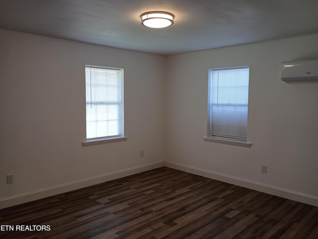 spare room with dark wood-type flooring, an AC wall unit, and baseboards