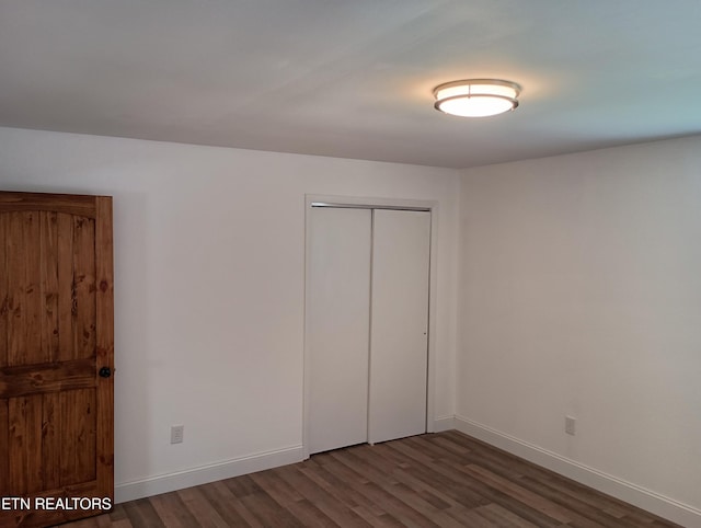 unfurnished bedroom featuring a closet, baseboards, and wood finished floors