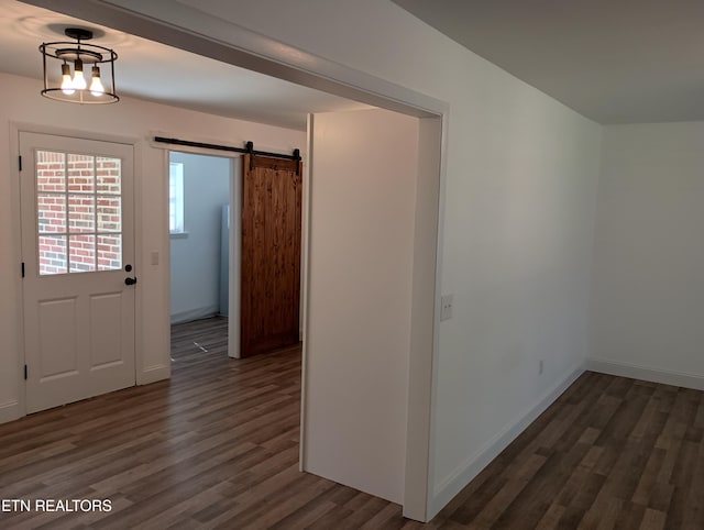 entryway with wood finished floors, baseboards, and a barn door