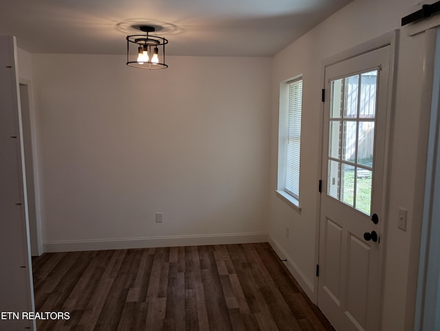 unfurnished dining area featuring baseboards and dark wood finished floors