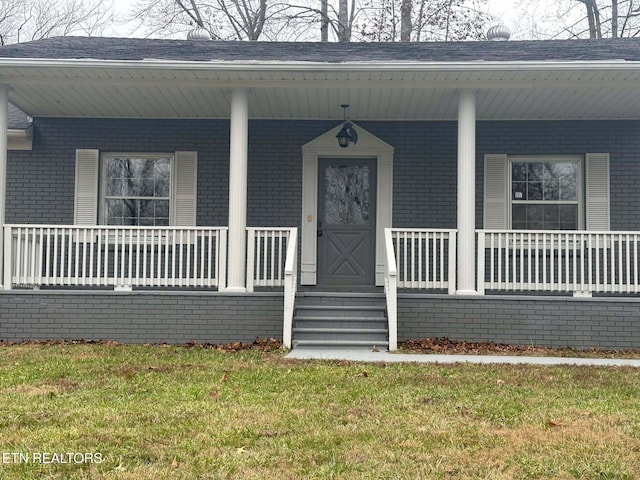 doorway to property featuring covered porch and a yard