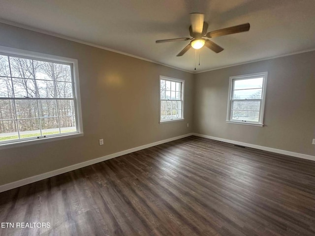 empty room with a healthy amount of sunlight, dark hardwood / wood-style flooring, and crown molding