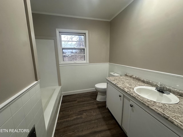 bathroom featuring vanity, a washtub, toilet, ornamental molding, and wood-type flooring