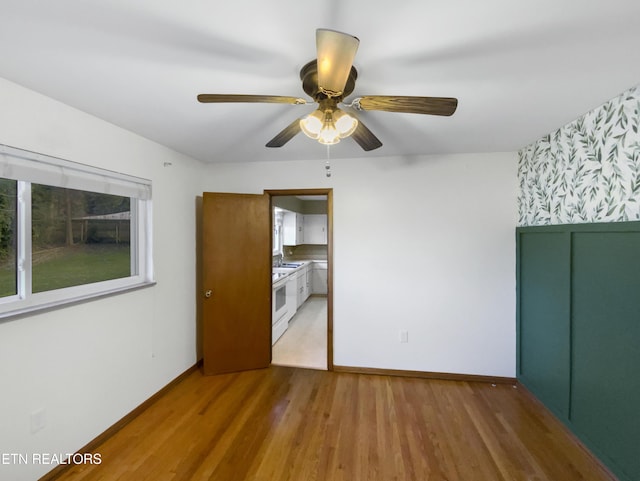 empty room featuring hardwood / wood-style flooring, ceiling fan, and sink