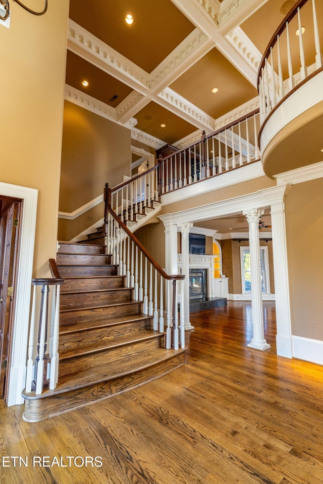 stairway with hardwood / wood-style floors, decorative columns, ornamental molding, and coffered ceiling