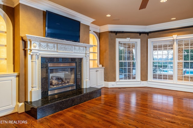 unfurnished living room with hardwood / wood-style flooring, ceiling fan, crown molding, and a fireplace