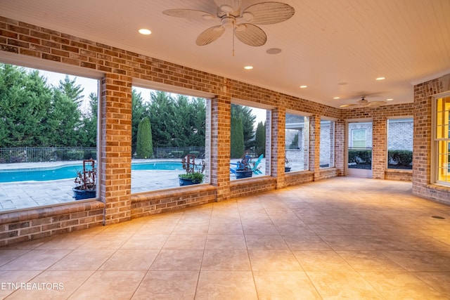 unfurnished sunroom with ceiling fan