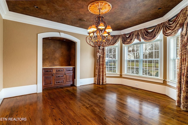 unfurnished dining area with dark hardwood / wood-style floors, crown molding, and an inviting chandelier