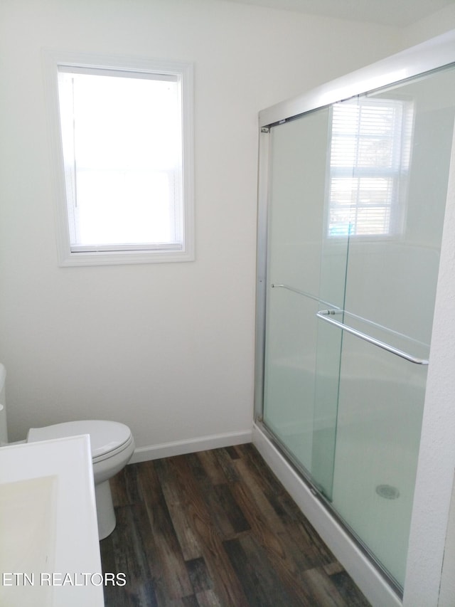 bathroom featuring hardwood / wood-style floors, a shower with door, and toilet