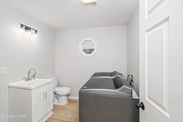 bathroom featuring hardwood / wood-style flooring, toilet, washing machine and dryer, and vanity