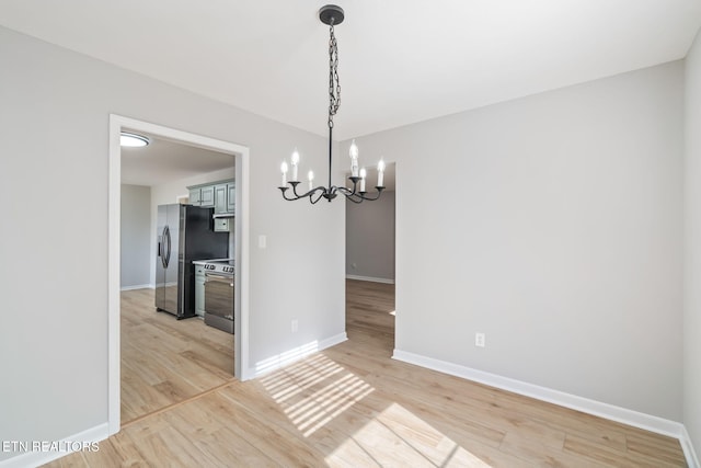unfurnished dining area featuring light hardwood / wood-style flooring and an inviting chandelier