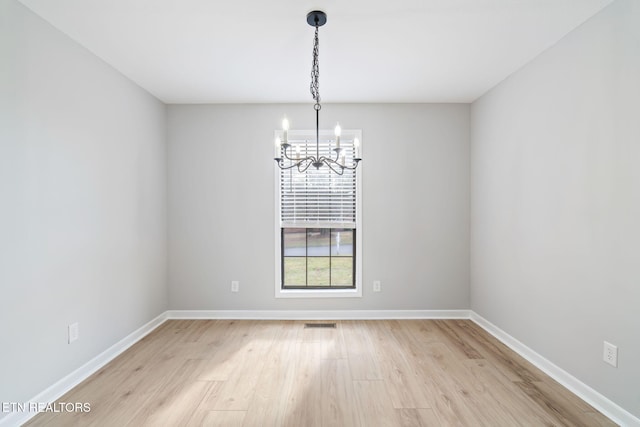 empty room featuring light hardwood / wood-style flooring and a chandelier