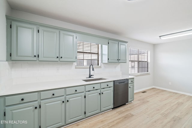kitchen with dishwasher, light wood-type flooring, tasteful backsplash, and sink