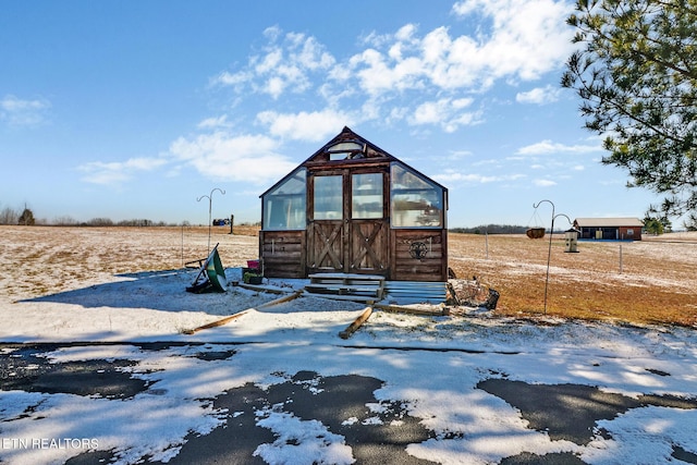 snow covered structure featuring a rural view