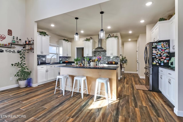 kitchen featuring white cabinets, dark hardwood / wood-style floors, a center island, and wall chimney range hood