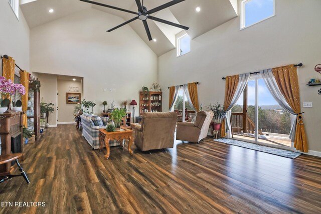 living room with a high ceiling, dark hardwood / wood-style flooring, and ceiling fan