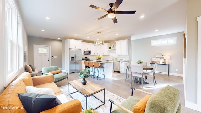 living room with sink, ceiling fan, and light wood-type flooring