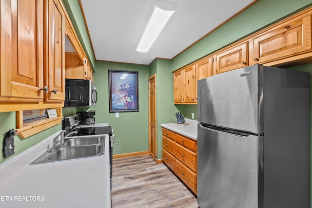 kitchen featuring stove, light hardwood / wood-style floors, stainless steel refrigerator, and sink