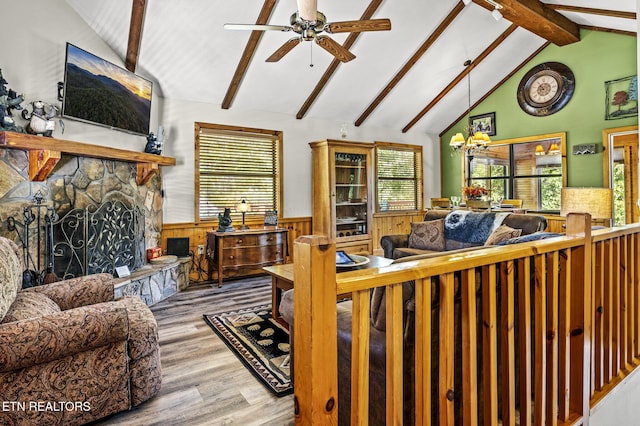 living room featuring vaulted ceiling with beams, a wealth of natural light, a stone fireplace, and light hardwood / wood-style floors