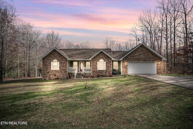 ranch-style home featuring covered porch, a yard, and a garage