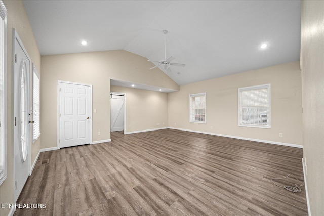 unfurnished living room with light wood-type flooring, vaulted ceiling, a wealth of natural light, and ceiling fan