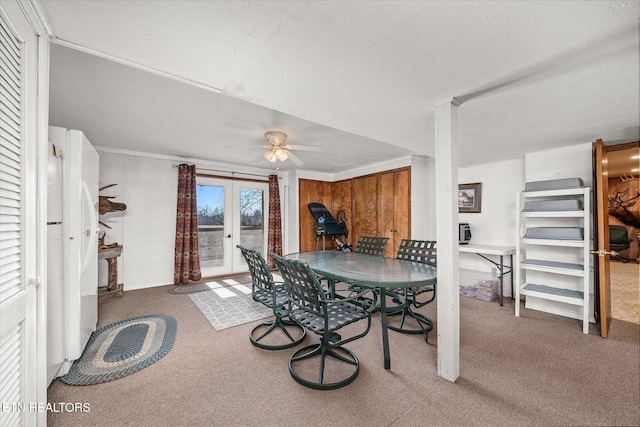 carpeted dining room featuring french doors, ceiling fan, and wooden walls