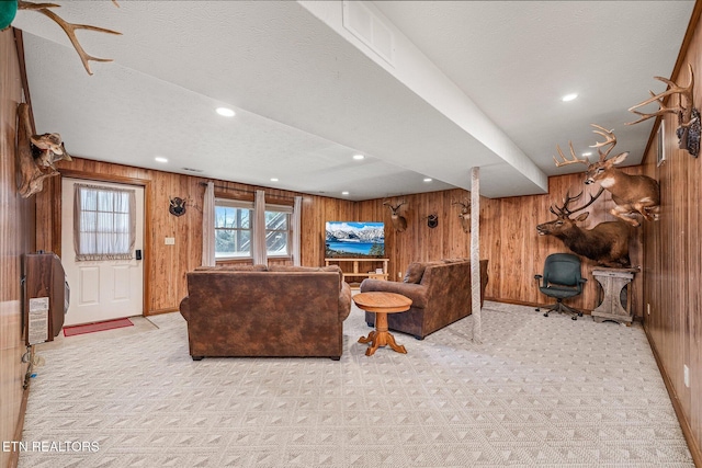 living room featuring a textured ceiling, wood walls, and light carpet