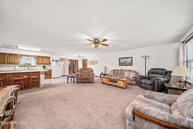 living room featuring light carpet, sink, and ceiling fan