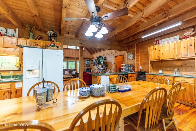 dining room featuring beam ceiling, ceiling fan, wooden walls, wood ceiling, and light wood-type flooring