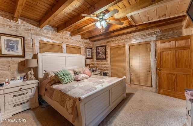 carpeted bedroom featuring beamed ceiling, ceiling fan, wooden ceiling, and wooden walls