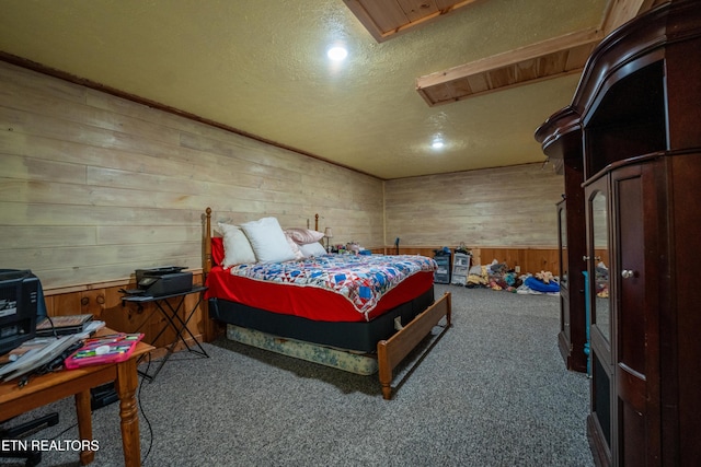 bedroom with carpet flooring, wooden walls, and a textured ceiling