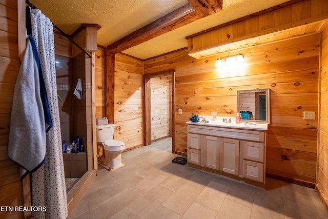 bathroom with a textured ceiling, vanity, a shower, beam ceiling, and wood walls