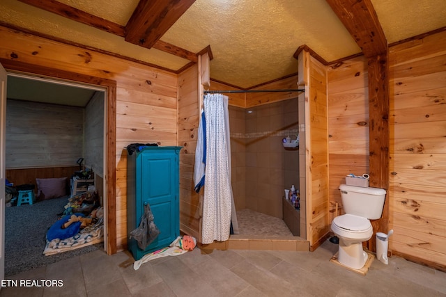 bathroom with beamed ceiling, a shower with shower curtain, wooden walls, and toilet