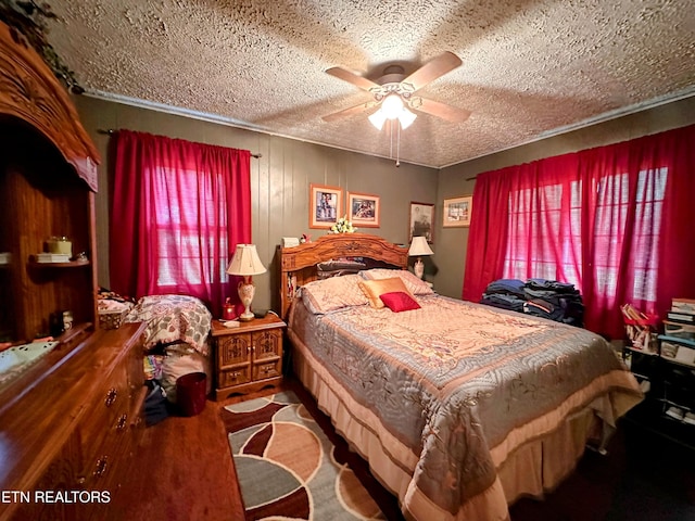 bedroom with a textured ceiling, ceiling fan, and wood walls