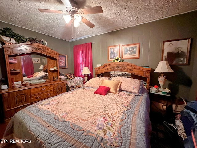 bedroom with ceiling fan, wooden walls, and a textured ceiling