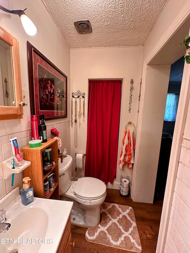 bathroom with vanity, toilet, wood-type flooring, and a textured ceiling