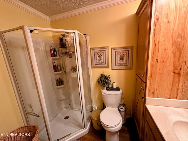 bathroom featuring a textured ceiling, toilet, a shower with door, and crown molding