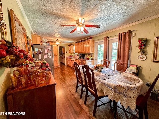 dining room featuring ceiling fan, light wood-type flooring, a textured ceiling, and ornamental molding