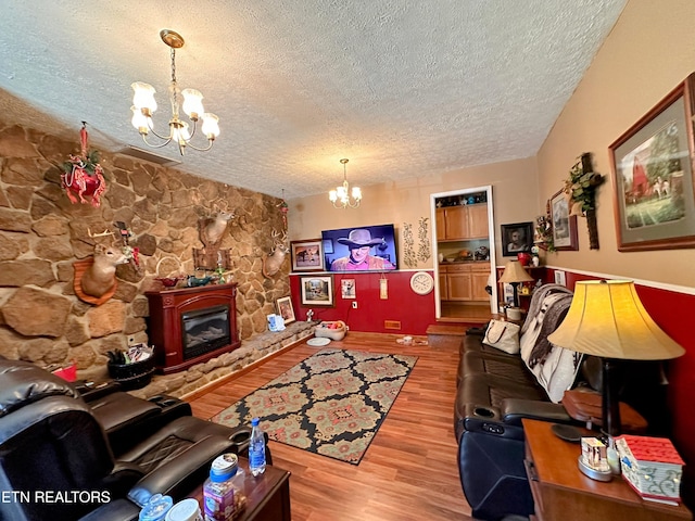 living room with a fireplace, wood-type flooring, a textured ceiling, and an inviting chandelier