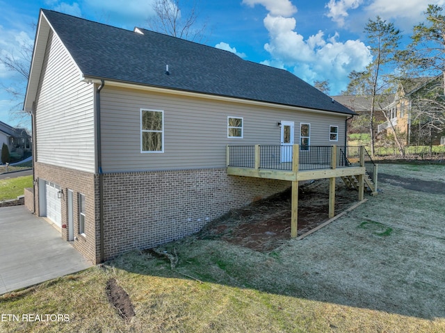 rear view of property featuring a garage, a yard, and a wooden deck