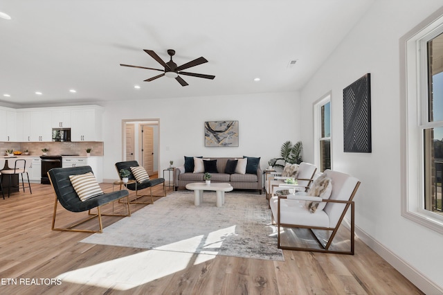 living room with ceiling fan and light hardwood / wood-style flooring