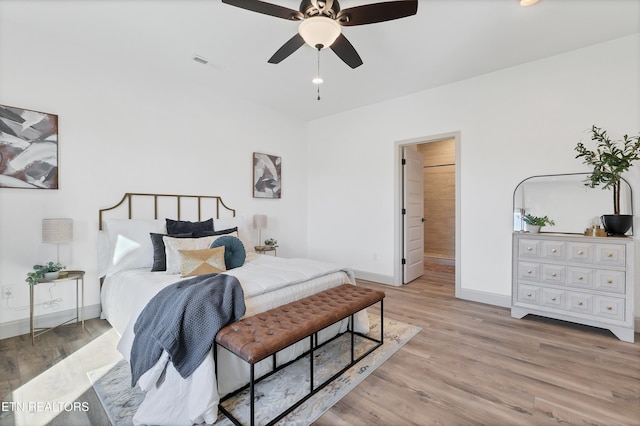 bedroom with ceiling fan, ensuite bathroom, and light hardwood / wood-style floors