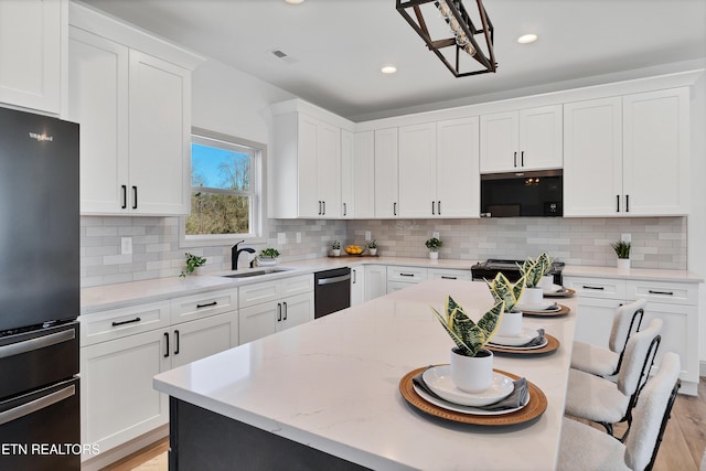 kitchen with white cabinets, refrigerator, sink, and tasteful backsplash