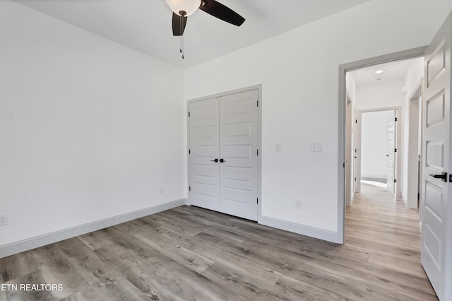 unfurnished bedroom with ceiling fan, light hardwood / wood-style flooring, and a closet