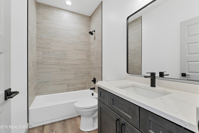 full bathroom with vanity, toilet, wood-type flooring, and tiled shower / bath