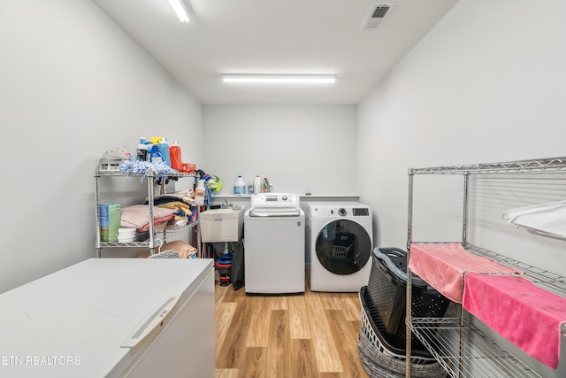 laundry room with sink, light wood-type flooring, and independent washer and dryer