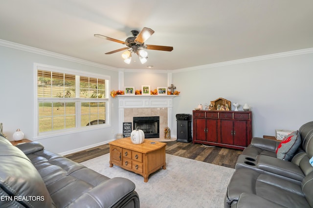 living room featuring a tile fireplace, crown molding, ceiling fan, and dark wood-type flooring