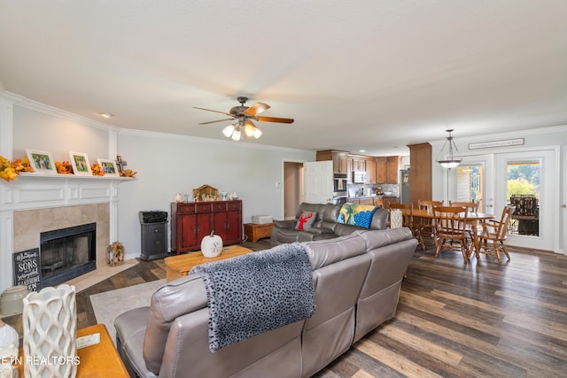 living room with ceiling fan, a fireplace, dark wood-type flooring, and ornamental molding