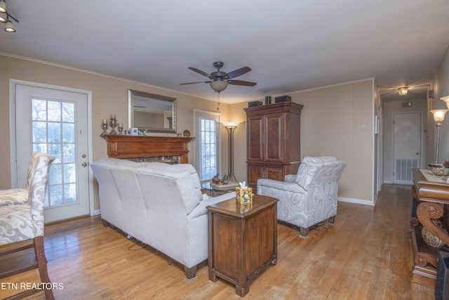 living room with ceiling fan, light hardwood / wood-style floors, ornamental molding, and a wealth of natural light